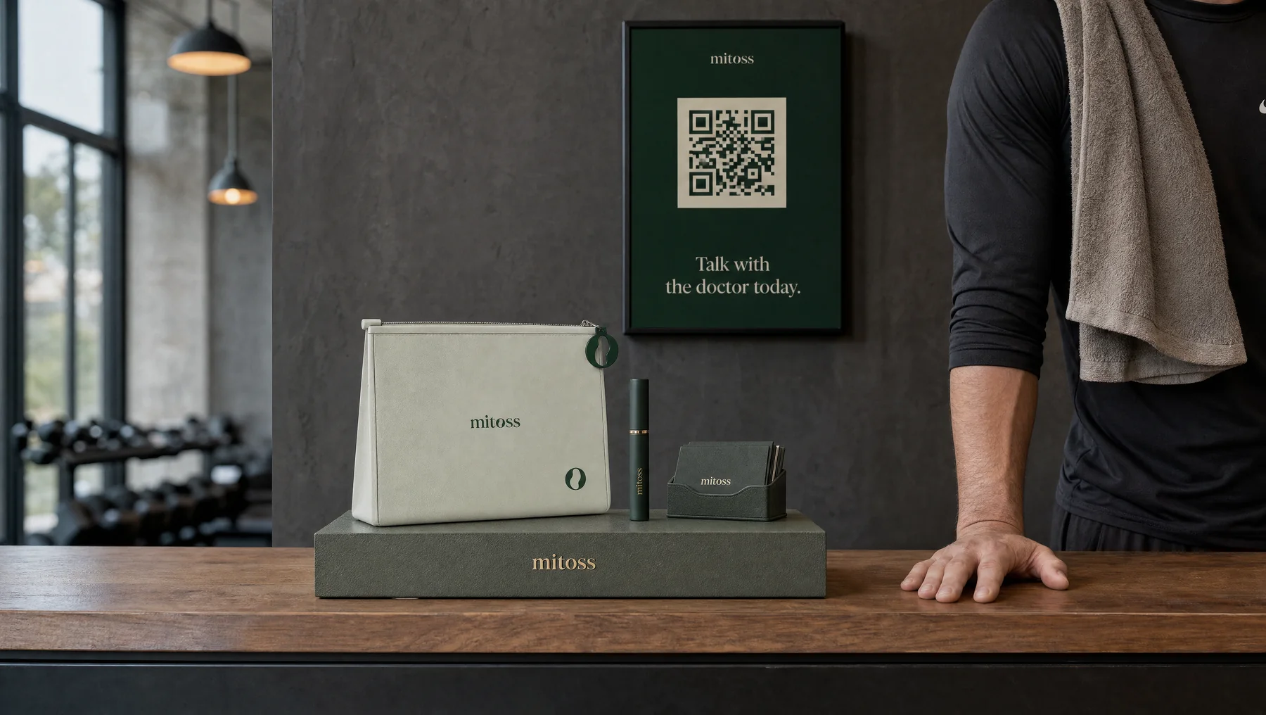 A gym front desk with the Mitoss pouch, a pen and a QR poster that reads Talk with the doctor today