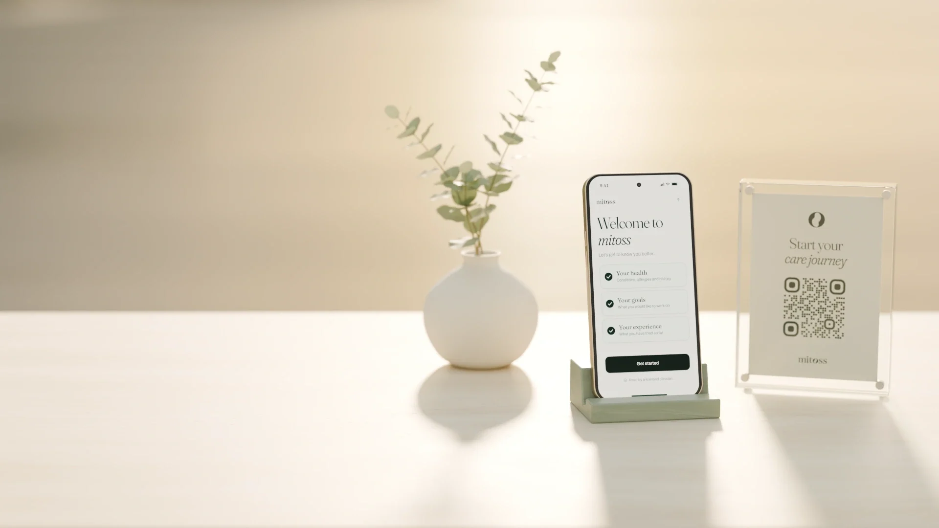 A phone on a stand showing the Mitoss intake, next to a small card with a QR code