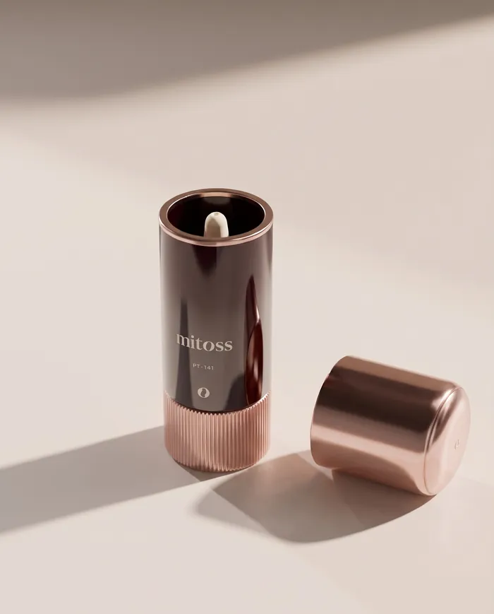 The rose-gold cap covers a cream nasal applicator on the burgundy bottle, seen from above